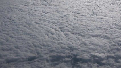 The view from the window of an airplane flying above the thick white clouds. Skyscape