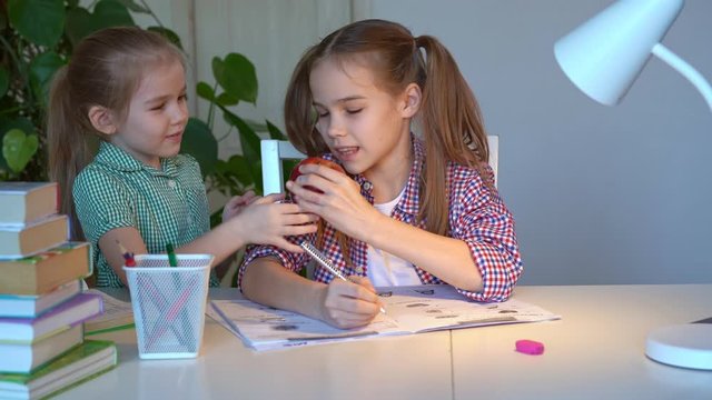 the younger sister brought the older apple for a snack. children learn at home remotely. remote training in quarantine. the social distance.