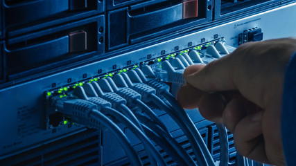 Macro Shot: Person Plugs in RJ45 Internet Connector into LAN Router Switch. Information Communication Network with Data Cables Connected to Modem Ports with Flashing Lights