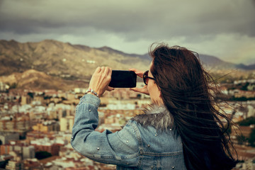 Young woman tourist photographs the landscape with her phone Mediterranean Europe