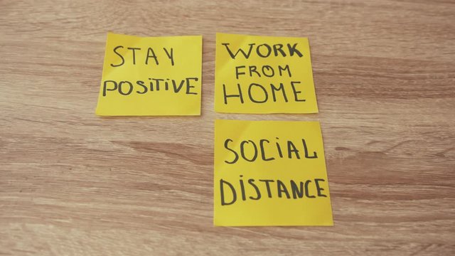 Stay Positive. Social Distance. Work From Home. Stay at Home. Business motivation words on yellow sticker notes at wooden background. Handwritten inscription.