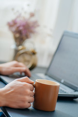 Office desk table with laptop computer, coffee cup and flower.