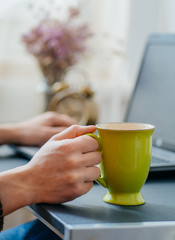 working  on laptop in office and drinking coffee