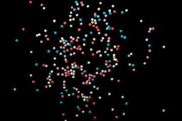 multicolored confectionery sprinkle in the form of stars on a black background