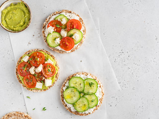 Vegetarian open sandwiches with fresh vegetable, avocado and tofu cheese on round crispy whole grain bread decorated with olive oil, pepper and green thyme. Top view food, flat layout, copy space.