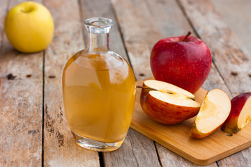 Apple organic vinegar in glass pitcher with ripe fresh red and yellow apples on wooden rustic table. Healthy organic food concept