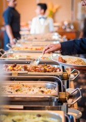 A person serving his meal to a white plate from a buffet in a hotel