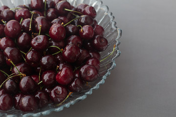 Fresh cherry in a glass vase on a gray horizontal background