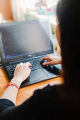 Young caucasian girl in black sweater looking at computer while studying online at hom