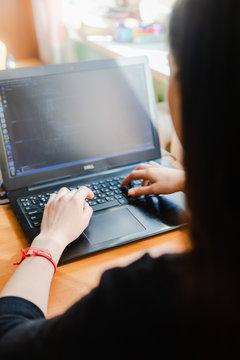 Young caucasian girl in black sweater looking at computer while studying online at hom