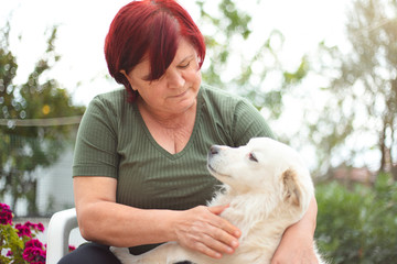 mature woman spends pleasant time in the garden of her house with her cute dog.