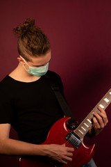 Coronavirus, quarantine at home, playing guitar in protection mask