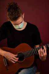 Coronavirus, quarantine at home, playing guitar in protection mask