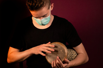 Coronavirus, quarantine at home, playing drums in protection mask