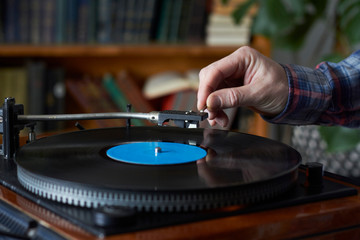 Male hand placing the needle on a record plate, selective focus
