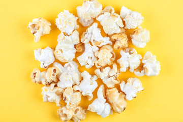 Caramel popcorn isolated on a yellow background, scattered. Mockup, frame of popcorn, top view.