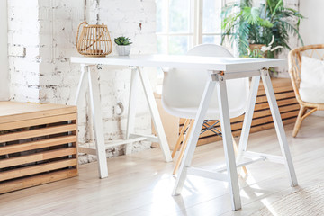 Stylish loft modern home office interior. Spacious design apartment with light walls large windows and writing desk. Clean modern decoration with elegant furniture in minimalist Scandinavian style.