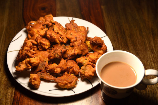 Chai with pakoras and bhajiyas and served on plate on wooden background