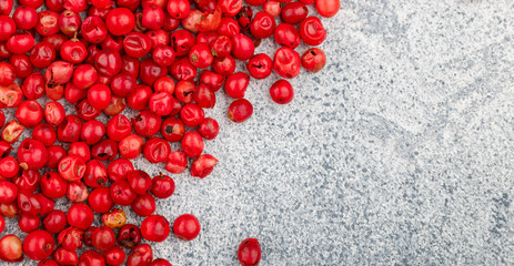 Pink Organic dried Peppercorns  on a light concrete or stone background close-up. Spices and seasonings. Selective focus, top view and copy space