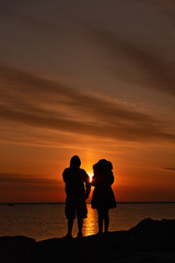 Alone together social distancing couple silhouette by the lake shore 