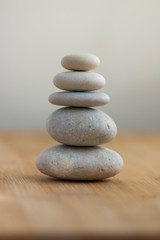 Fototapeta na wymiar Stone cairn on striped grey white background, five stones tower, simple poise stones, simplicity harmony and balance,