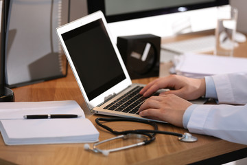 Professional doctor working on laptop in office, closeup