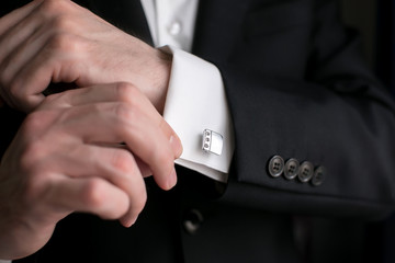 Close-up of a man in a tux fixing his cufflink. groom bow tie cufflinks