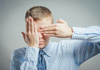 Fototapeta premium young man closes his eyes with his hands