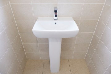 A white sink sitting next to a tiled wall