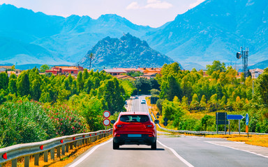 Scenery with red car on highway in Cagliari Sardinia hills reflex