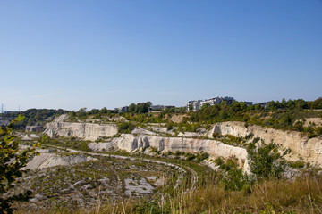 Fototapeta na wymiar Some buildings stand at the edge of the limestone quarry called Kalkbrottet in Malmö, Sweden. The area is no longer in use, and now a nature reserve