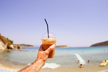young man holding a cocktail in hand on the beach in vacation.