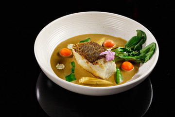 Lentil soup with baby corn, peeled tomato cherries, green leaves and salmon chunk.  in a white bowl black background. Food photography appetizer dish for online menu delivery concept.