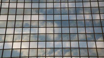 Facade of a modern building with windows mirroring the sky and the clouds