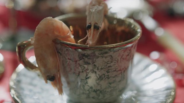 prawns in a tea set, sunbeams playing on them. the image of mediocre luxury, excess, gluttony, bad taste. Shot with RED camera