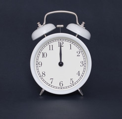 Old-style alarm clock, black and white, it's twelve o'clock.