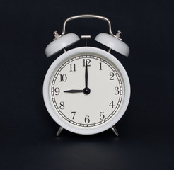 Old-style alarm clock, black and white, it's nine o'clock.
