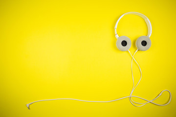 White audio headphones with a 3.5 mm wire on a yellow background
