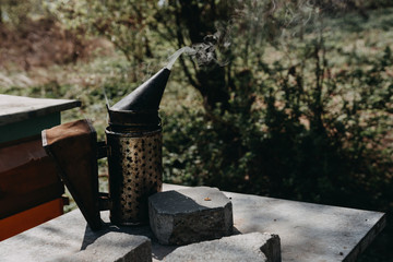 Chimney for flashing bees. Chimney stands near beehives.The beekeeper's tool. Bee smoker smoking.