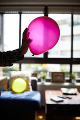 A hand holds a red balloon.
