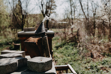 Chimney for flashing bees. Chimney stands near beehives.The beekeeper's tool. Bee smoker smoking.