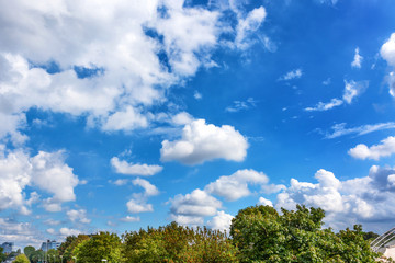 Fototapeta na wymiar Fluffy white clouds on background of blue sky over the park.