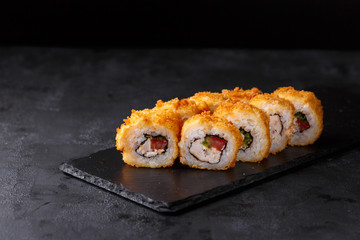 Sushi rolls with smoked chicken, rice, nori,cucumber, tomato, salad and mayonnaise. on a black slate.