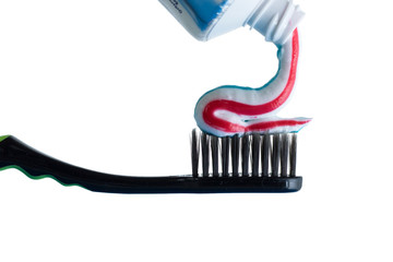 Toothpaste is applied to the toothbrush. Multi-colored toothpaste and black toothbrush isolated on white background. The concept of hygiene and caries prevention.