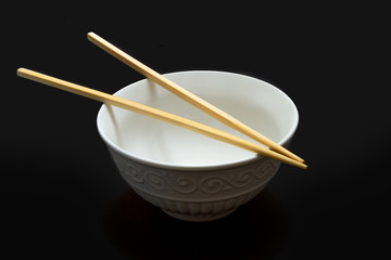 Chopsticks on a white empty rice bowl