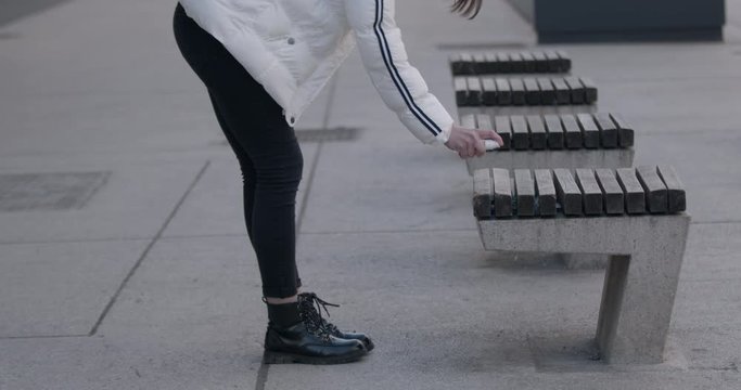 Fear of getting the coronavirus - Girl disinfects a bench before sitting on it to be safe