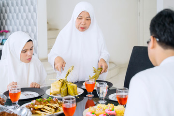 Obraz na płótnie Canvas Old mother cutting ketupat in dining room