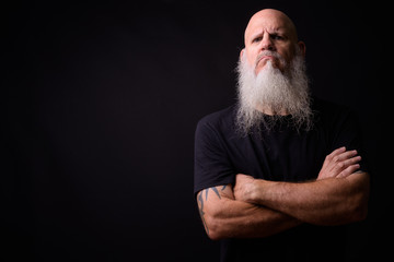 Mature bald bearded man against black background