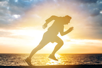 Silhouette of a running young man in sportswear at sunset. Sport lifestyle