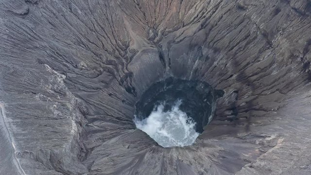 View from above, stunning aerial view of the Mount Bromo with clouds of gases raising from the crater. Mount Bromo is an active volcano in East Java, Indonesia.	